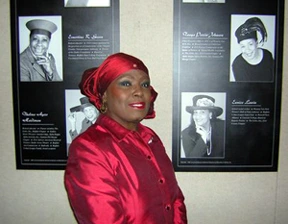 Photo of Dr. Peggy Brooks-Bertram in front of Uncrowned Queens display.