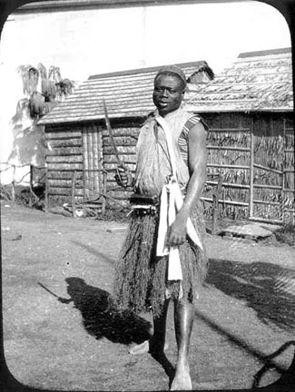 Man dressed in traditional African attire, holding a sword.