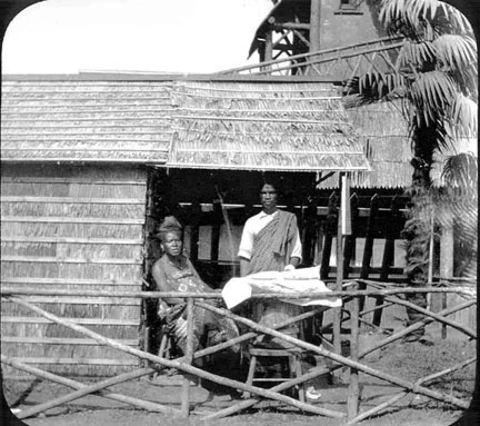 Two people under a straw house.