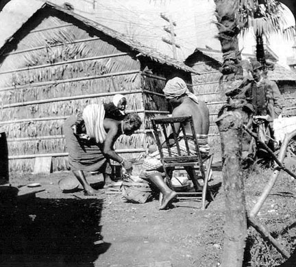A woman with a baby on her back, and a man in a chair.