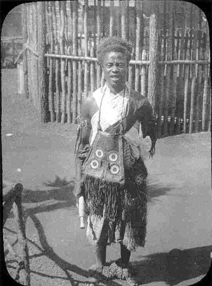 A person stands in traditional African attire.
