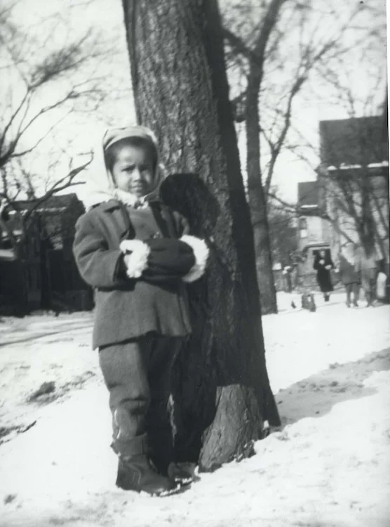 Barbara A. Seals Nevergold as a child standing by a tree in winter.